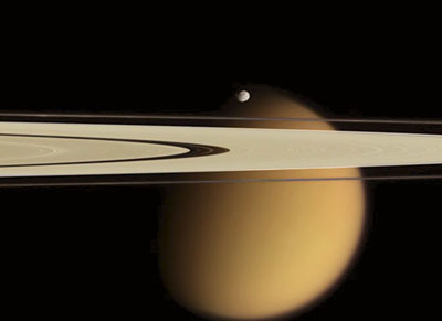 Saturn's rings and the moon Epimetheus in front of the cloud-covered moon Titan